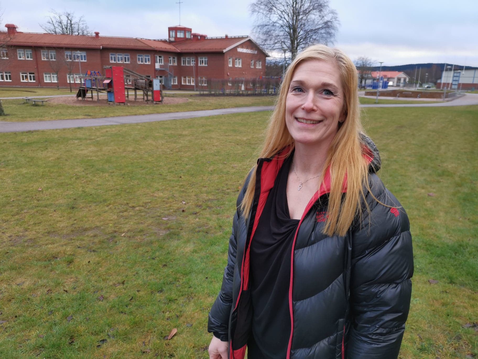 Kvinna står framför Vargbroskolan i disigt väder