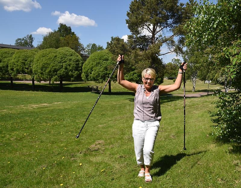 Hälsokonsulent Pia Aspvik står på en gräsmatta med vandringsstavar.