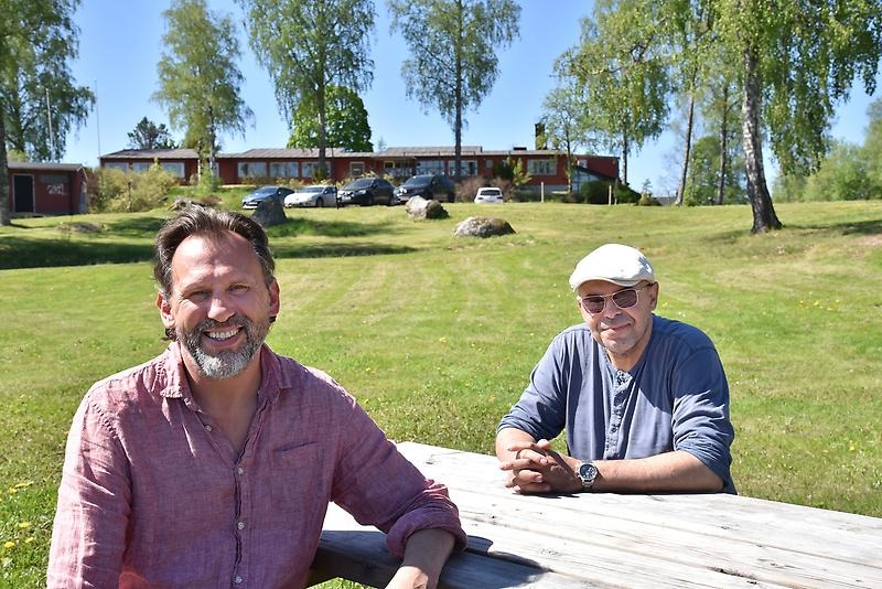 Två män sitter vid ett bord framför Lungsunds camping och hotell.