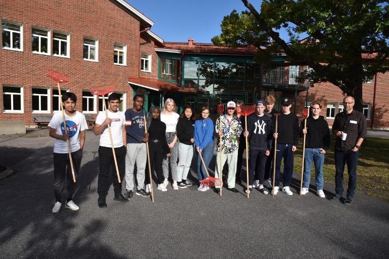 Niondeklassare i Storfors står på skolgården med krattor i högsta hugg