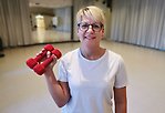 Kvinna i motionslokal med två röda hantlar i handen